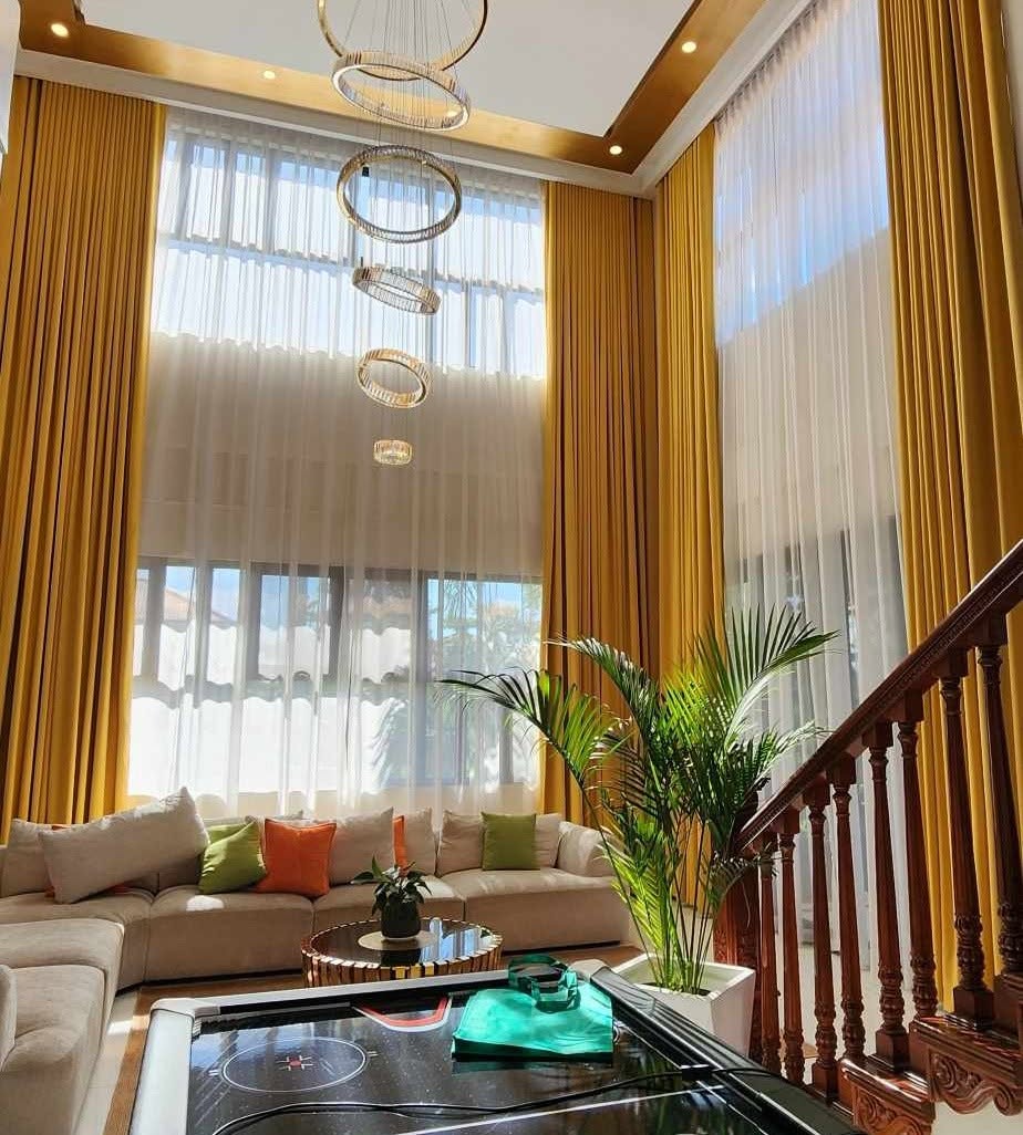 Double-height floor-to-ceiling curtains: golden yellow drapes with white sheers in a grand luxury living room