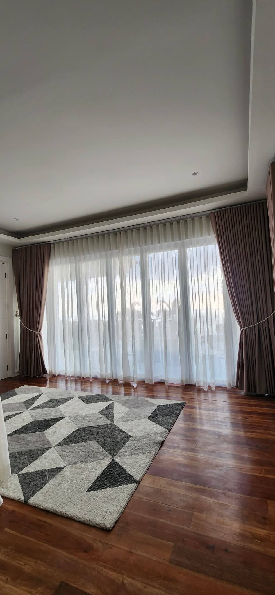 Floor-to-ceiling custom curtains: brown blackout drapes with S-fold sheer curtains on large glass windows
