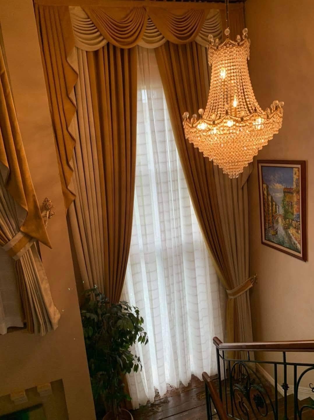 Classic gold layered curtains with valance and sheer in a grand stairwell
