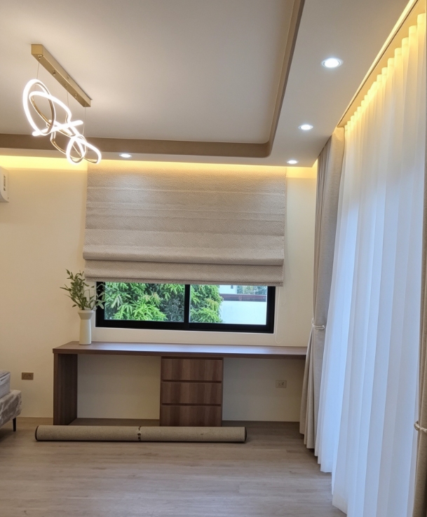 Modern room with Roman blind, beige blackout drapes and white S-fold sheers, clean lighting control