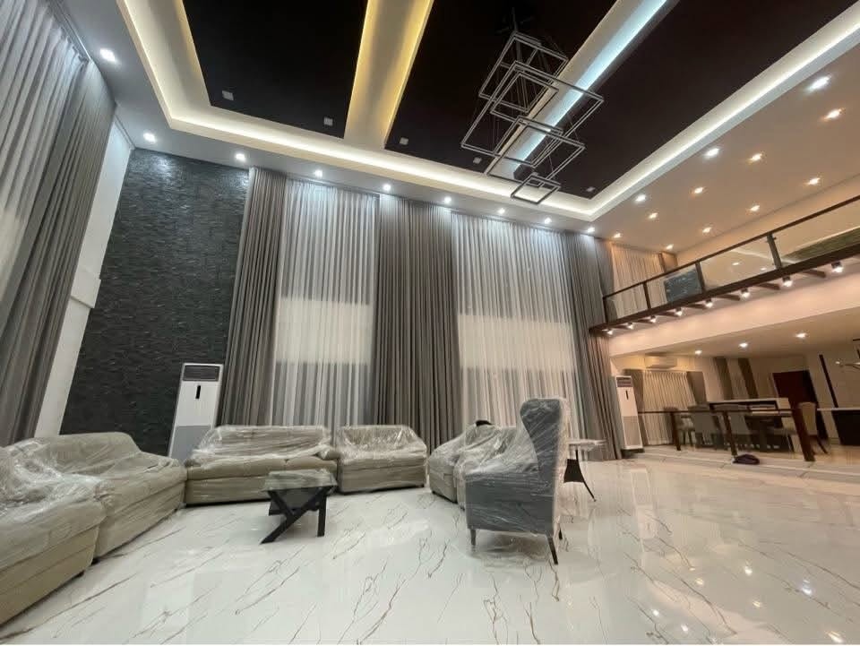 Ultra tall floor-to-ceiling curtains: light gray drapes + S-fold sheers in a modern double-volume living area